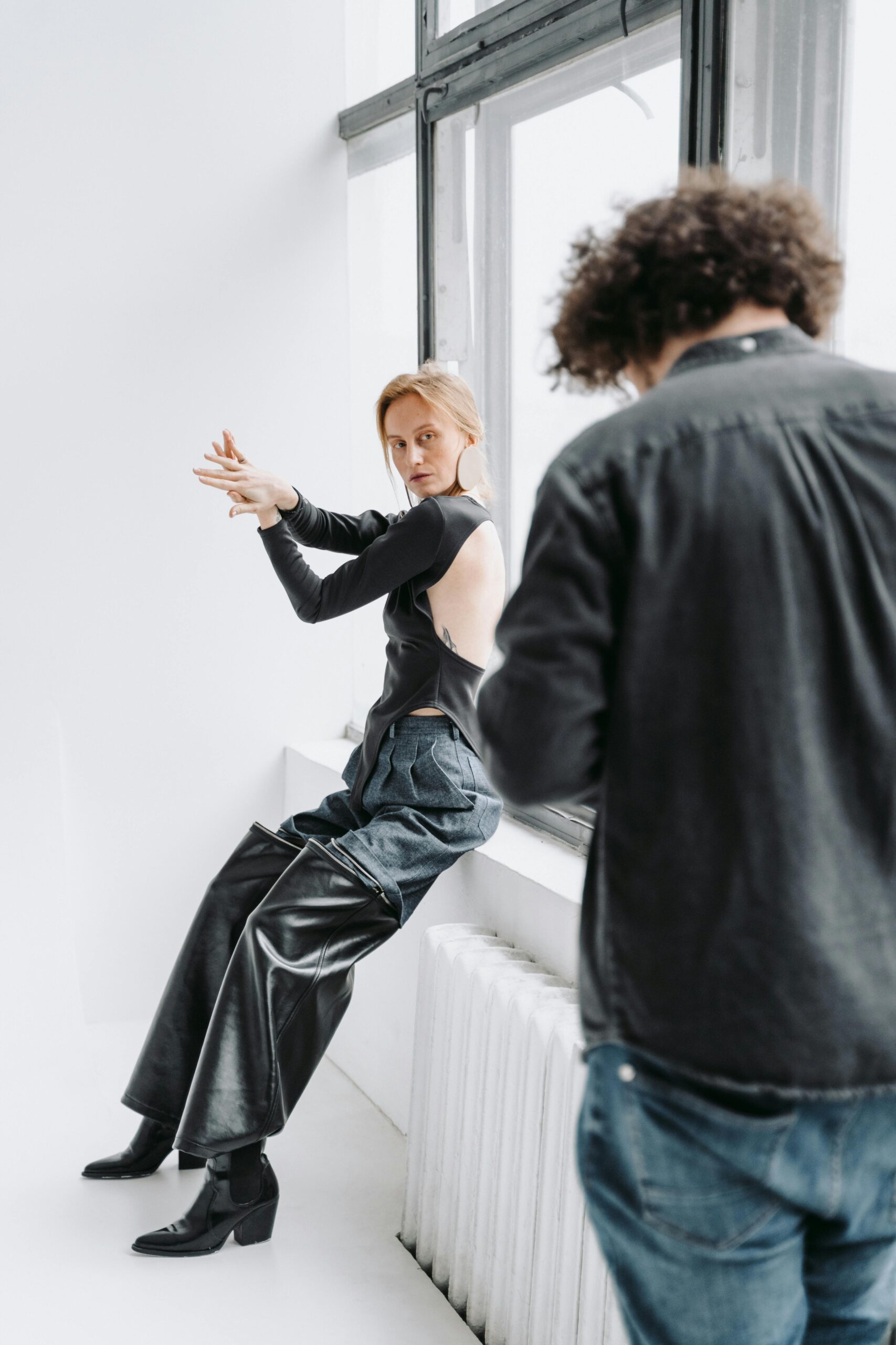 Woman posing in a modern fashion shoot with photographer in a bright studio setting.